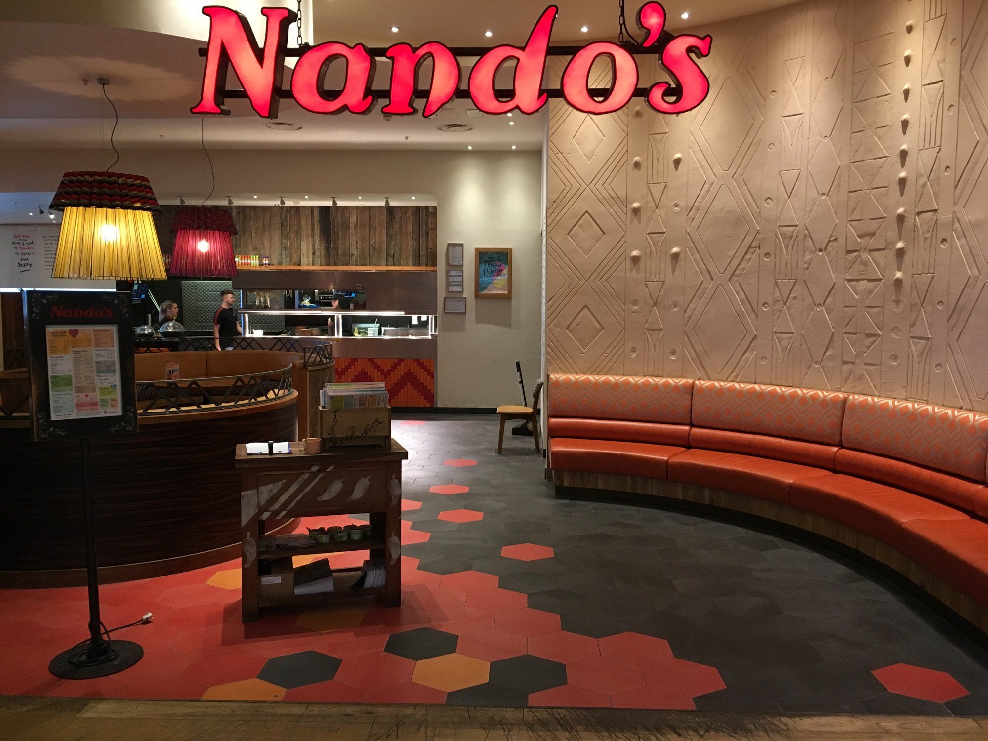 Custom printed hexagon ceramic floor tiles in red, orange and charcoal at a Nando’s restaurant
