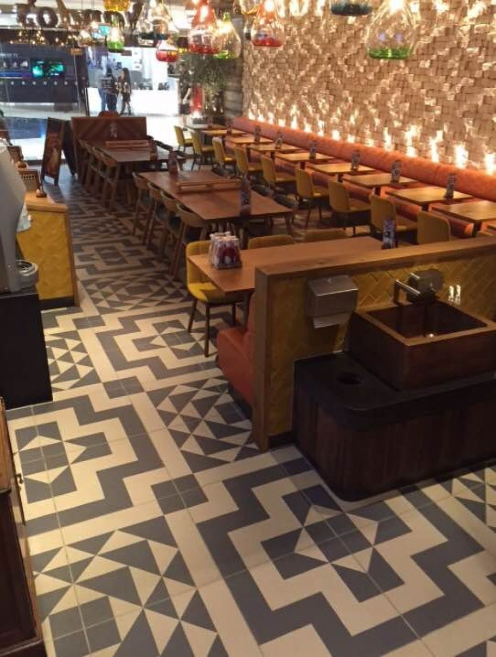 Grey and white geometric printed ceramic floor tiles in a busy restaurant seating area